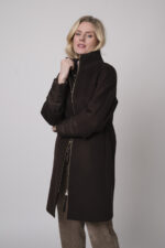 Das Model trägt einen Stehkragenpullover von Hemisphere in Sand, dazu eine Cordhose von Cambio in Camel und einen braunen Mantel von Joop.