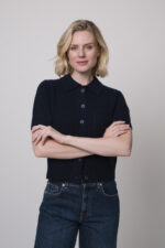 Das Model trägt eine Jeans von 7 for all mankind und eine Strickweste von True Religion in Marine.