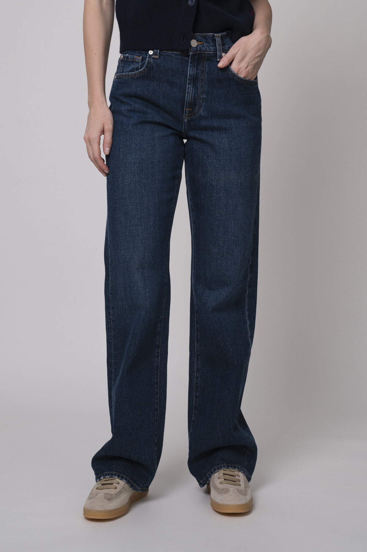 Das Model trägt eine Jeans von 7 for all mankind und eine Strickweste von True Religion in Marine.