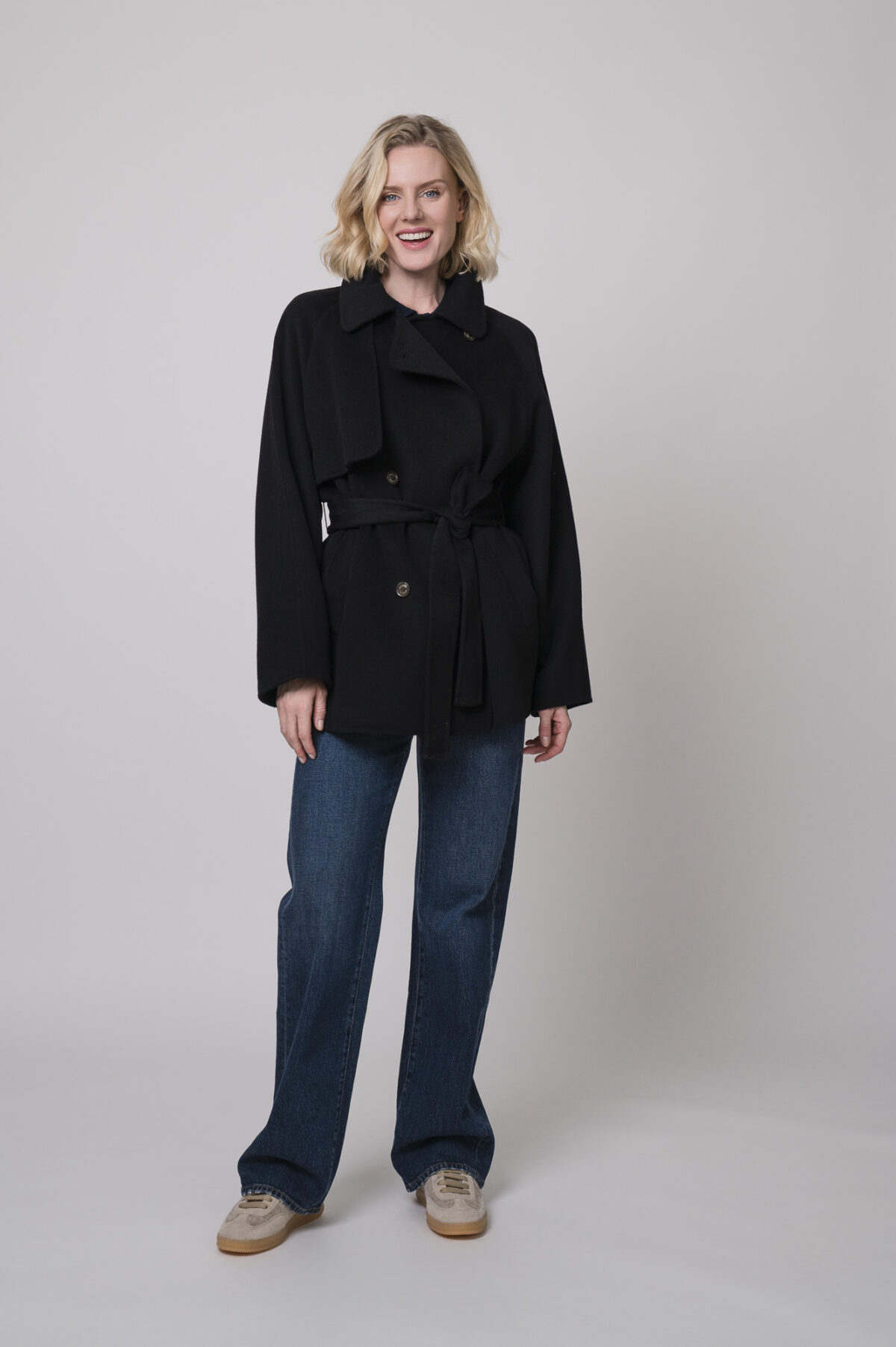 Das Model trägt eine Jacke von Helmur in schwarz, eine Jeans von 7 for all mankind und eine Strickweste von True Religion in Marine.