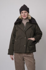 Das Model trägt eine Jacke von Lou Andrea, eine Cordhose von Cambio in Camel, einen Stehkragenpullover von Hemisphere in Sand sowie eine Haube von FFC.