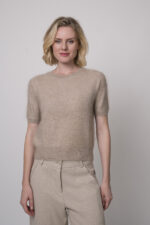 Das Model trägt eine sportliche Hose von Cambio in Sand sowie einen Camel-Pullover von Absolut Cashmere.