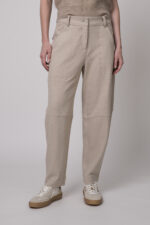 Das Model trägt eine sportliche Hose von Cambio in Sand sowie einen Camel-Pullover von Absolut Cashmere.