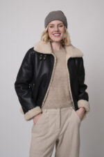 Das Model trägt eine schwarze Jacke von Joop, eine Haube von FFC sowie eine sportliche Hose von Cambio in Sand, und einen Camel-Pullover von Absolut Cashmere.