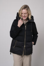 Das Model trägt eine schwarze Daunenjacke von Duno, eine sandfarbene Hose von Cambio und einen Pullover von Absolut Cashmere in Camel.