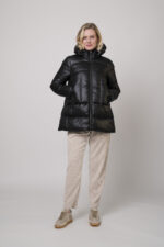 Das Model trägt eine Daunenjacke von Helmur in Mittelblau sowie eine Cordhose von Camio in der Farbe Sand und Sneaker von Voile Blanche.