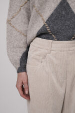 Das Model trägt einen Pullover von Luisa Cerano mit Rautenmuster in Anthrazit sowie eine Cordhose von Cambio in Natur.