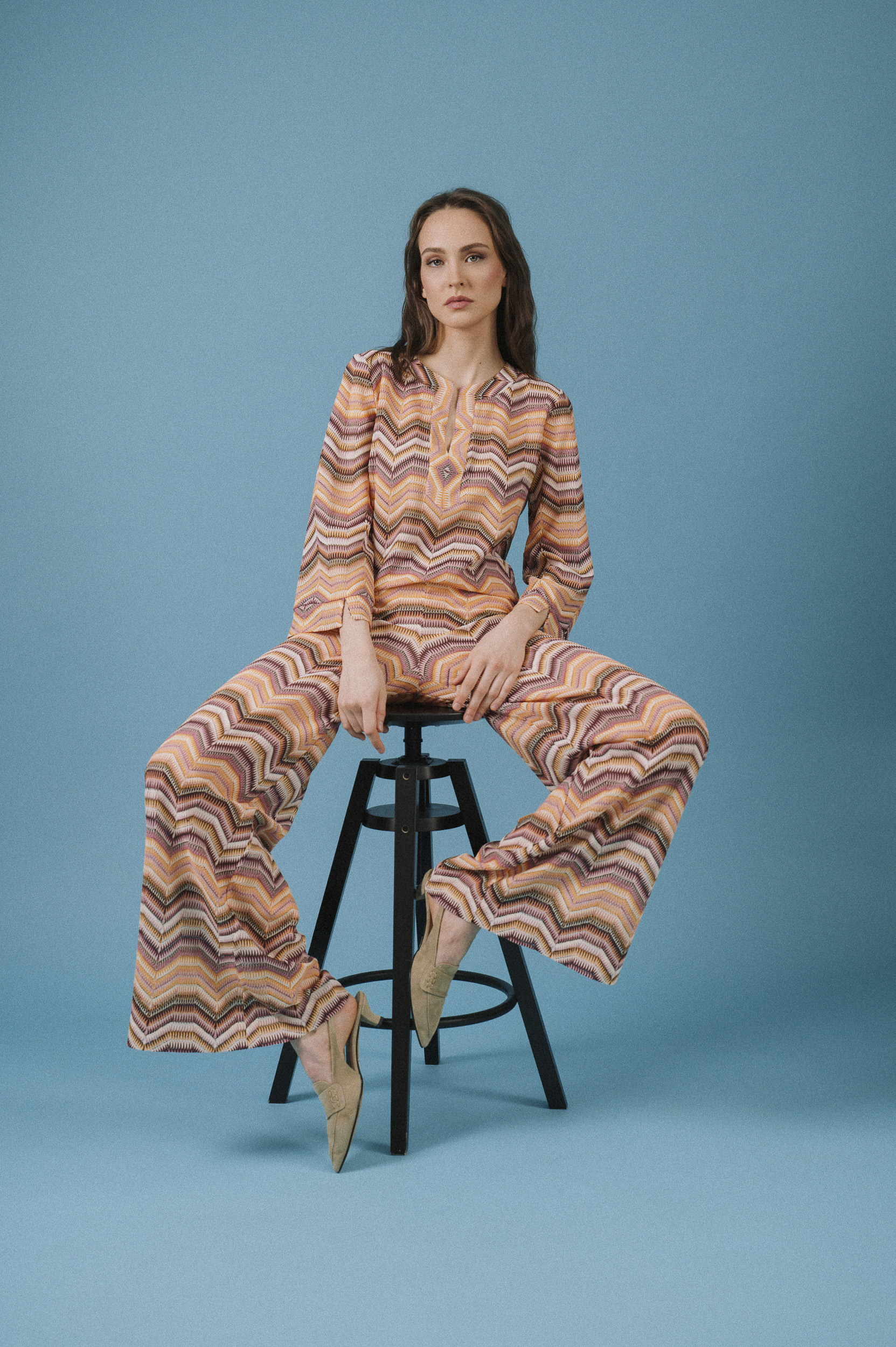 Model trägt ein Strickoberteil und eine Strickhose mit Zick-Zach-Muster der Marke Ana Alcazar.