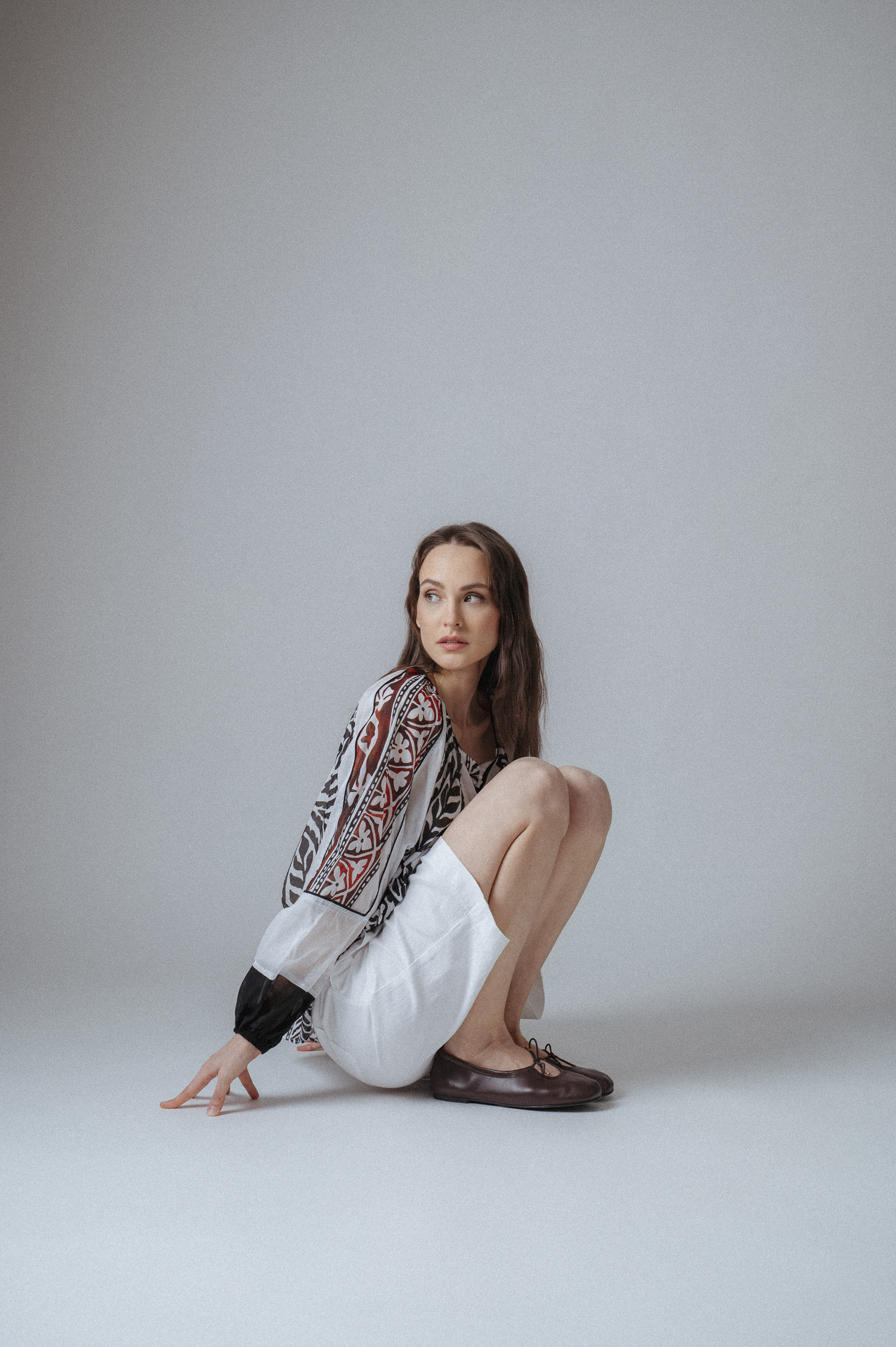 Model zeigt eine weiße Bermudas der Marke Luisa Cerano und eine bunte Bluse der Marke Devotion.