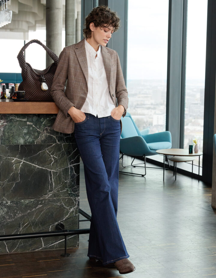 Model trägt einen braun karierten Blazer der Marke Circolo, eine weiße Bluse der Marke Wendy Stark und eine blaue Jeans der Marke True Religion