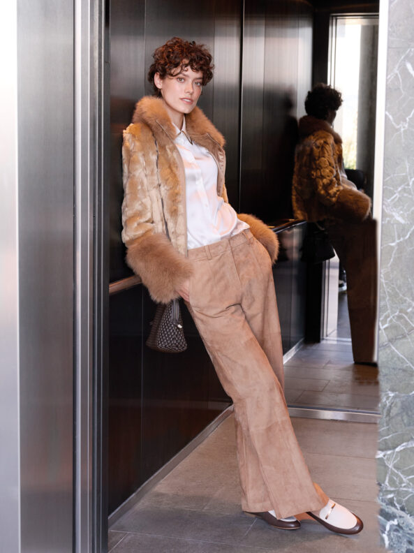 Model trägt ein Outfit der Marke Marc Cain - eine beige Jacke, eine weiße B luse und eine beige Hose.