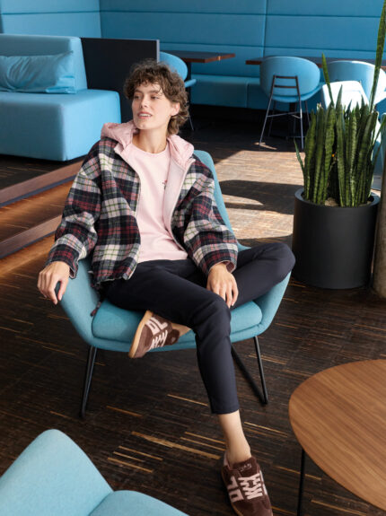 Model trägt ein Outfit von Marc Cain - eine rosa, schwarz und weiß karierte Jacke, ein rosa Oberteil und eine dunkelblaue Hose