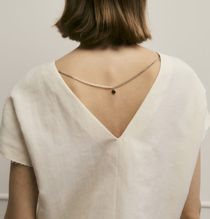 Model zeigt Oberteil von hinten mit Ketten-Detail in creme der Marke Luisa Cerano.
