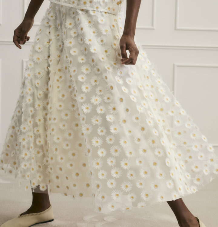 Model trägt Rock mit Gänseblümchen Ornamenten der Marke Luisa Cerano.